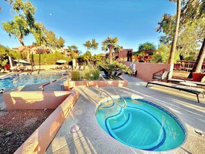 Ein Swimmingpool mit Whirlpool, umgeben von Liegestühlen und Palmen.