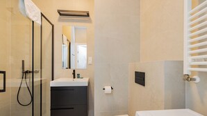 A modern bathroom with a glass shower enclosure, a white sink, a toilet, and a built-in towel rack. - ShortStayPoland Zdziechowskiego B152 (Warsaw)