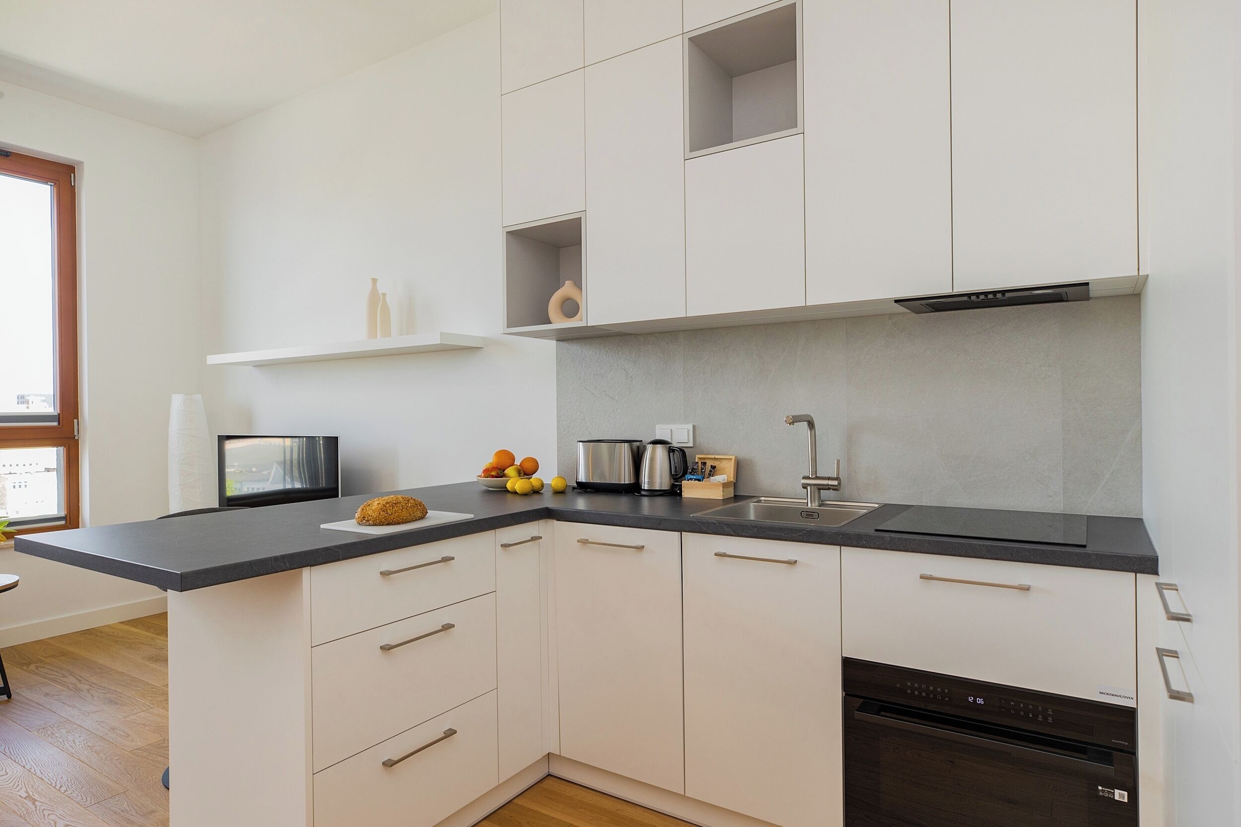 Une cuisine moderne avec des meubles blancs, un plan de travail noir et des appareils électroménagers en acier inoxydable.