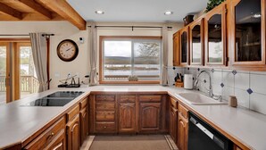A kitchen with wooden cabinets, a built-in stove, a large window, and a view of the outdoors. - Lakefront | Private Dock | Family Friendly | Kayaks | Hot Tub | Row Boat | Fireplace (Lake Ariel)