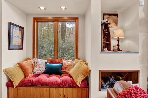 A cozy seating area with a cushioned bench, a wooden bench, and a fireplace.