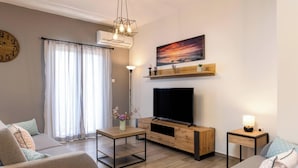A modern living room with a sofa, TV, and a wooden TV stand.