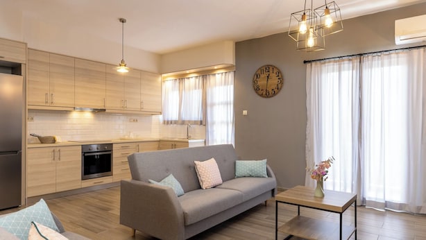 A modern kitchen with wooden cabinets, a built-in oven, and a dining area with a sofa and a coffee table.