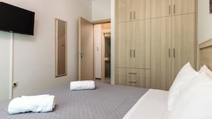 A hotel room with a bed, a TV, a wardrobe, and a mirror.