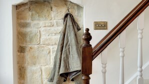 A staircase with a stone wall and a coat hanging on a hook. - The Coach House : Cosy Cottage Retreat (Bakewell)