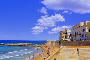 A beach with people, a clear sky, and buildings in the background. - Happy Camp in Camping La Vecchia Torre (Gallipoli)