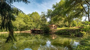 Une cabane au bord d’un lac paisible, entourée d’une forêt dense.