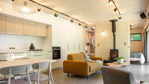 Une cuisine moderne avec des meubles blancs, une table à manger avec des chaises, un canapé et une cheminée.