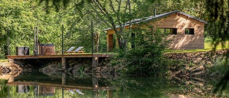 A wooden cabin by a lake with a deck and a small boat.