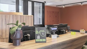 A reception desk with a B&B sign, a computer, a printer, and a plant. - B&B Hotel Prato City Center (Prato)