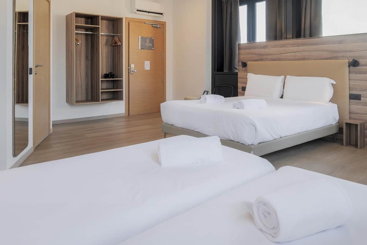 Une chambre d’hôtel avec deux lits, une armoire en bois et un grand miroir.