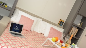 A neatly made bed with a laptop, a tray with fruits and drinks, and a book on the nightstand. - Central Apartment Guisan in Paradiso (Paradiso)