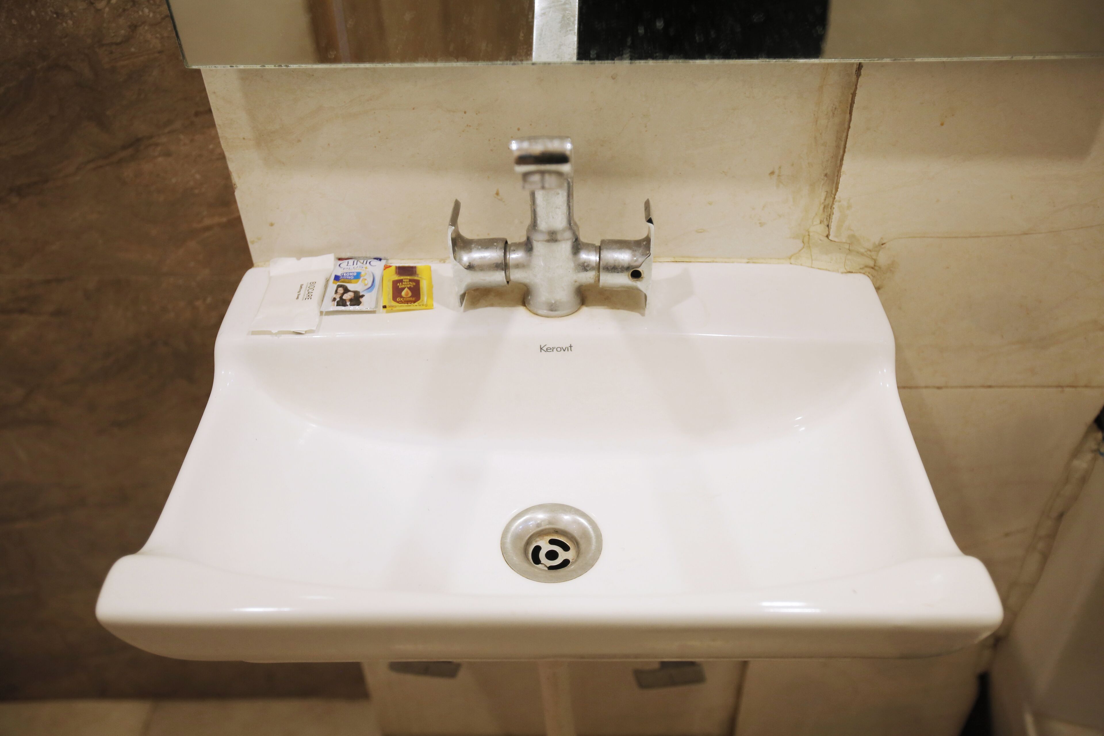 A white bathroom sink with a single faucet, a drain, and a label on the left side.