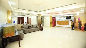 A spacious lobby with a reception desk, a fish tank, and a sofa. - Hotel Aman Inn (New Delhi)