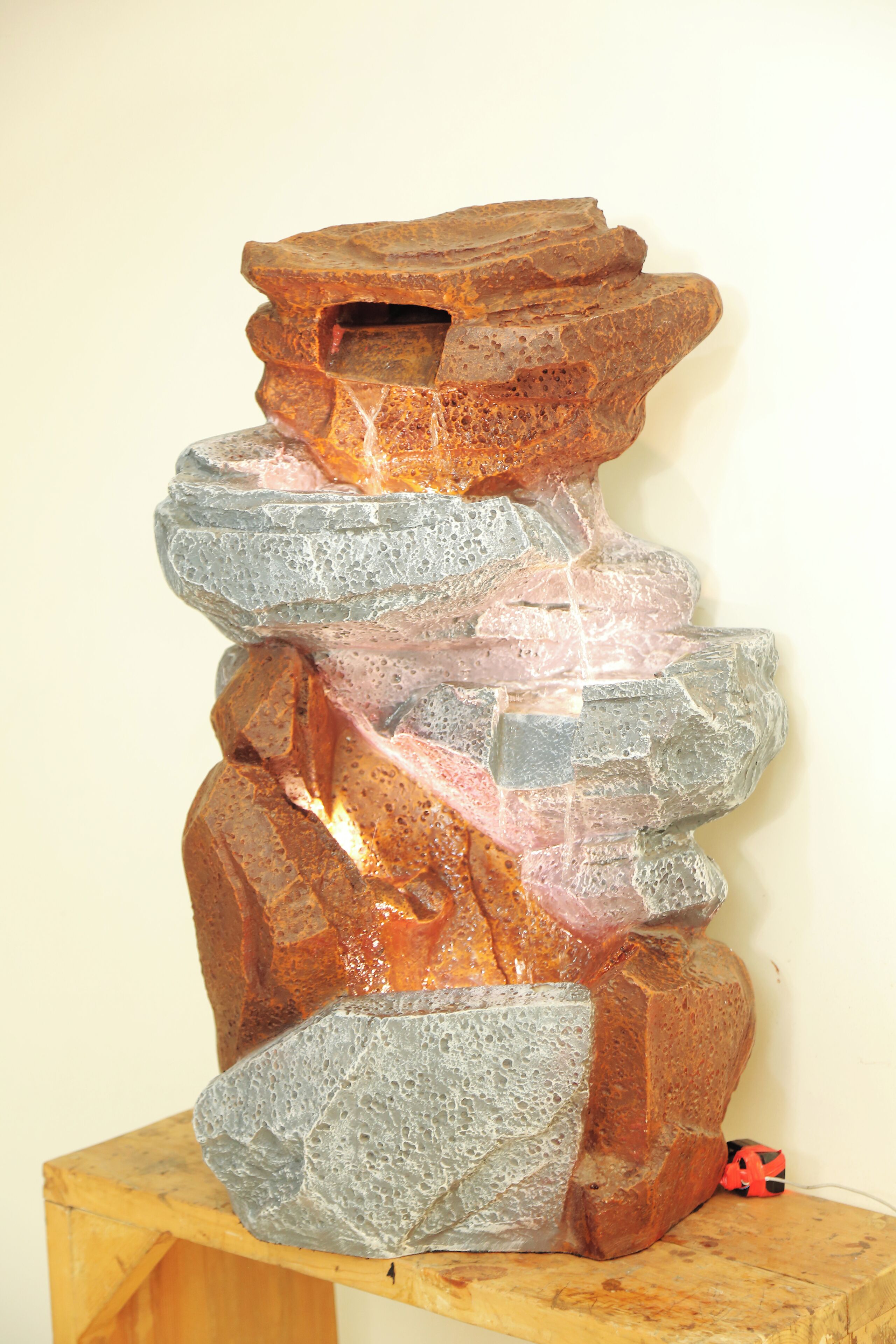 A sculpture with a rough texture and irregular shapes, placed on a wooden stand.