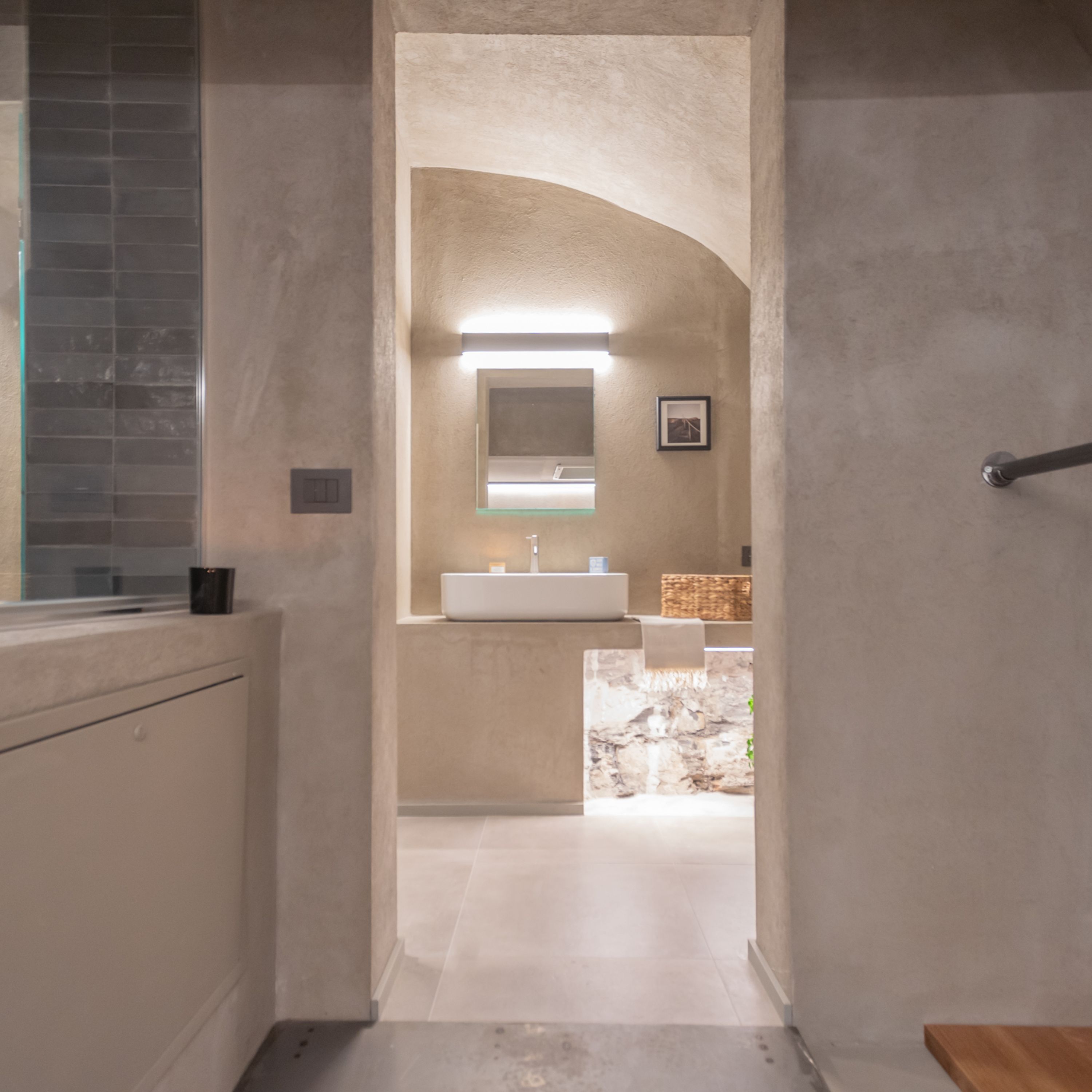 Un baño moderno con un espejo grande, un lavabo y una pared de detalles de piedra.