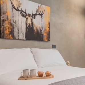 A bed with white linens, a painting of a moose, and a tray with two mugs and two muffins. - Gaia Suite Nearby Urio s Castle (Carate Urio)