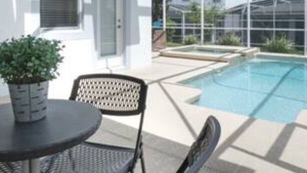 A covered outdoor area with a pool, a table, and chairs. - CG 1557 Mulligan Magical Retreat 5BR Pool Spa Near Disney (Davenport)