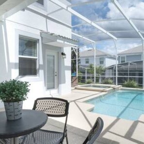 A covered outdoor area with a pool, a table, and chairs. - CG 1557 Mulligan Magical Retreat 5BR Pool Spa Near Disney (Davenport)