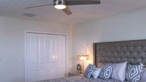 A bedroom with a bed, a ceiling fan, a nightstand, and a door. - CG 1557 Mulligan Magical Retreat 5BR Pool Spa Near Disney (Davenport)