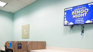 A room with a long table, wooden partitions, and a television displaying a 'Wednesday Bingo Night' sign. - CG 1557 Mulligan Magical Retreat 5BR Pool Spa Near Disney (Davenport)