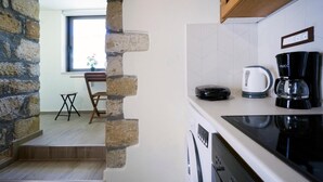 A kitchen with a stone wall, a coffee maker, and a kettle. - Kyriaki's Traditional House (Chania)