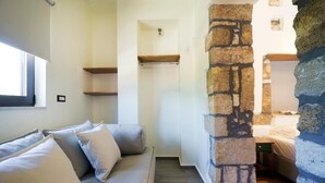 A cozy room with a stone pillar, a wooden shelf, a bed, and a sofa with cushions. - Kyriaki's Traditional House (Chania)