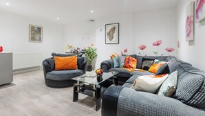 A modern living room with grey sofas, a glass coffee table, and decorative pillows. - Little Venice Maisonette (London)