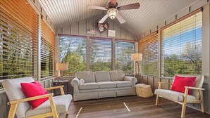 A cozy room with a sofa, two armchairs, a ceiling fan, and large windows with blinds. - Pet-Friendly · 3 Kings · Hot Tub · Arcade + Pool Table (Gatlinburg)