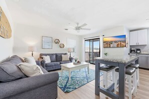 A living room with a gray sofa, a white coffee table, and a blue patterned rug.