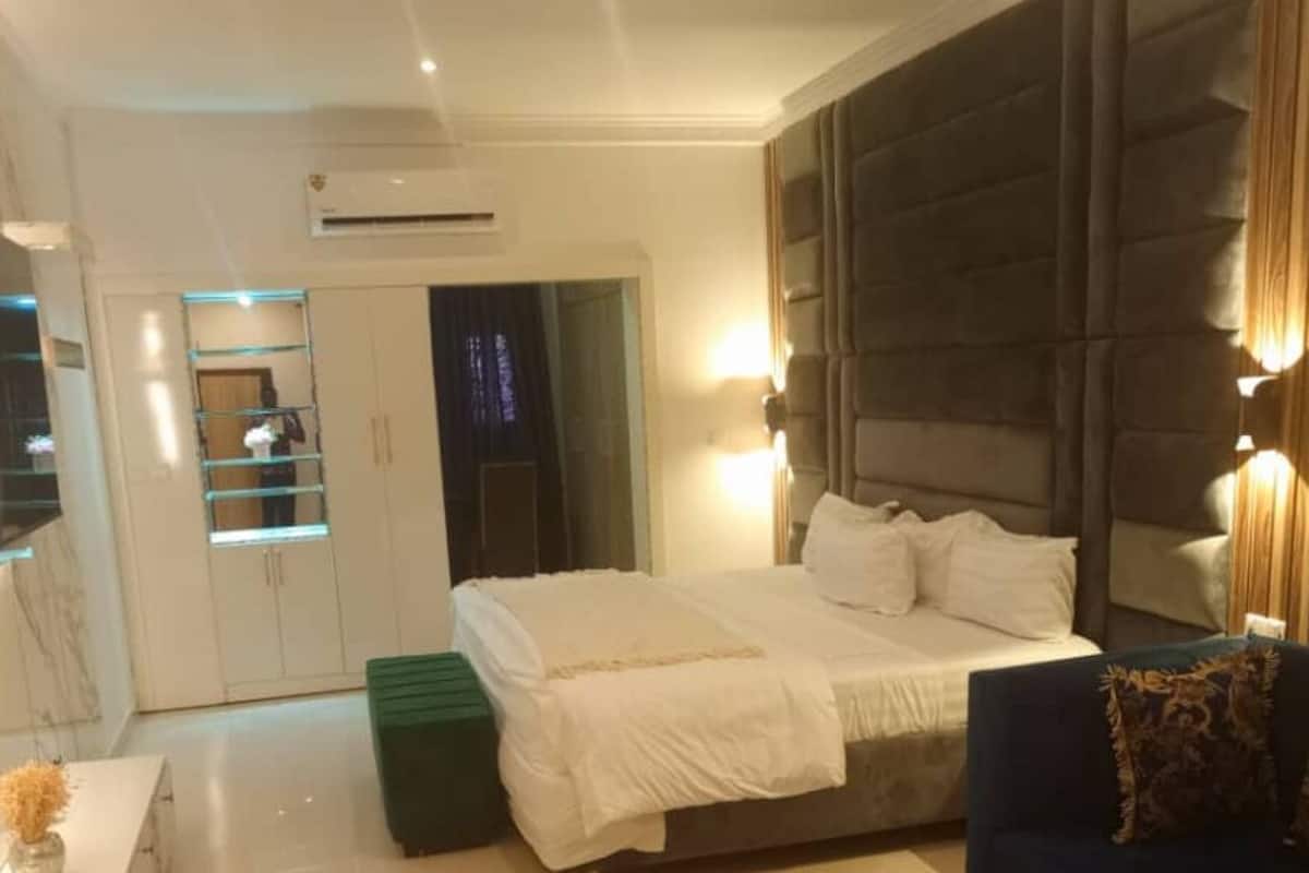 Un dormitorio moderno con una cama grande, un sofá, un armario y un espejo.