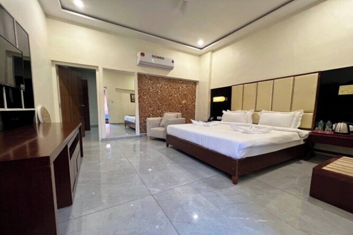 A modern hotel room with a large bed, a desk, a chair, and a minibar.