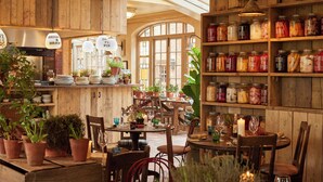 A rustic interior with wooden walls, a variety of potted plants, and shelves stocked with jars of preserved foods. - THE PIG at Bridge Place - Kent (Canterbury)