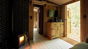 A rustic wooden interior with a fireplace, wooden cabinets, and a television. - THE PIG at Bridge Place - Kent (Canterbury)