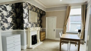 A room with a fireplace, a dining table, and a large window with curtains. - Entire 4-bed House in Sunderland (Sunderland)