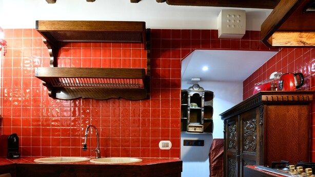 Une cuisine avec des carreaux rouges, des armoires en bois, un évier et une cuisinière.