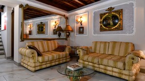 Un salon avec deux canapés, une table basse et des lampes fixées au mur.