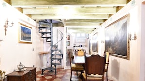 Un espace repas doté d’un sol carrelé à motifs hexagonaux, d’un escalier en colimaçon et d’une table à manger avec des chaises.