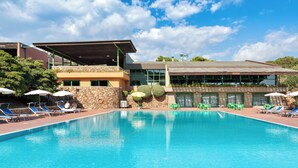 A swimming pool with lounge chairs and umbrellas, surrounded by a stone wall and a building with large windows. - Ecovillage with swimming-pool in Teulada (Teulada)