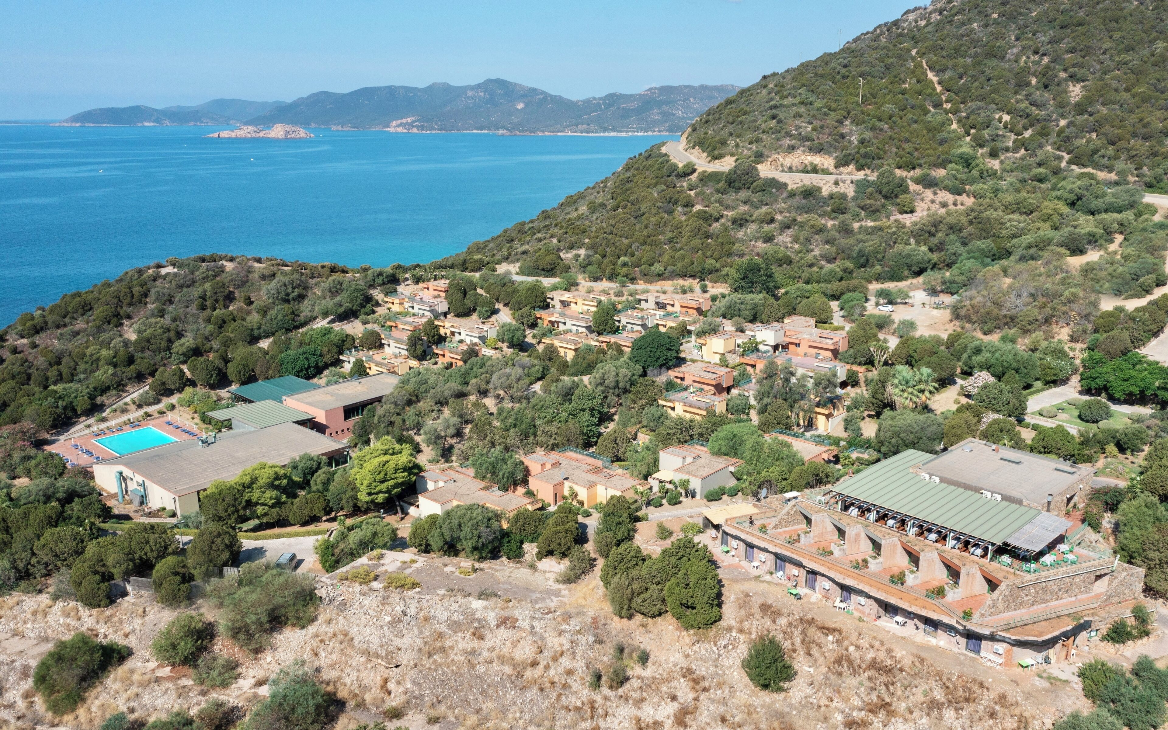 A coastal residential area with houses, a swimming pool, and a view of the sea.