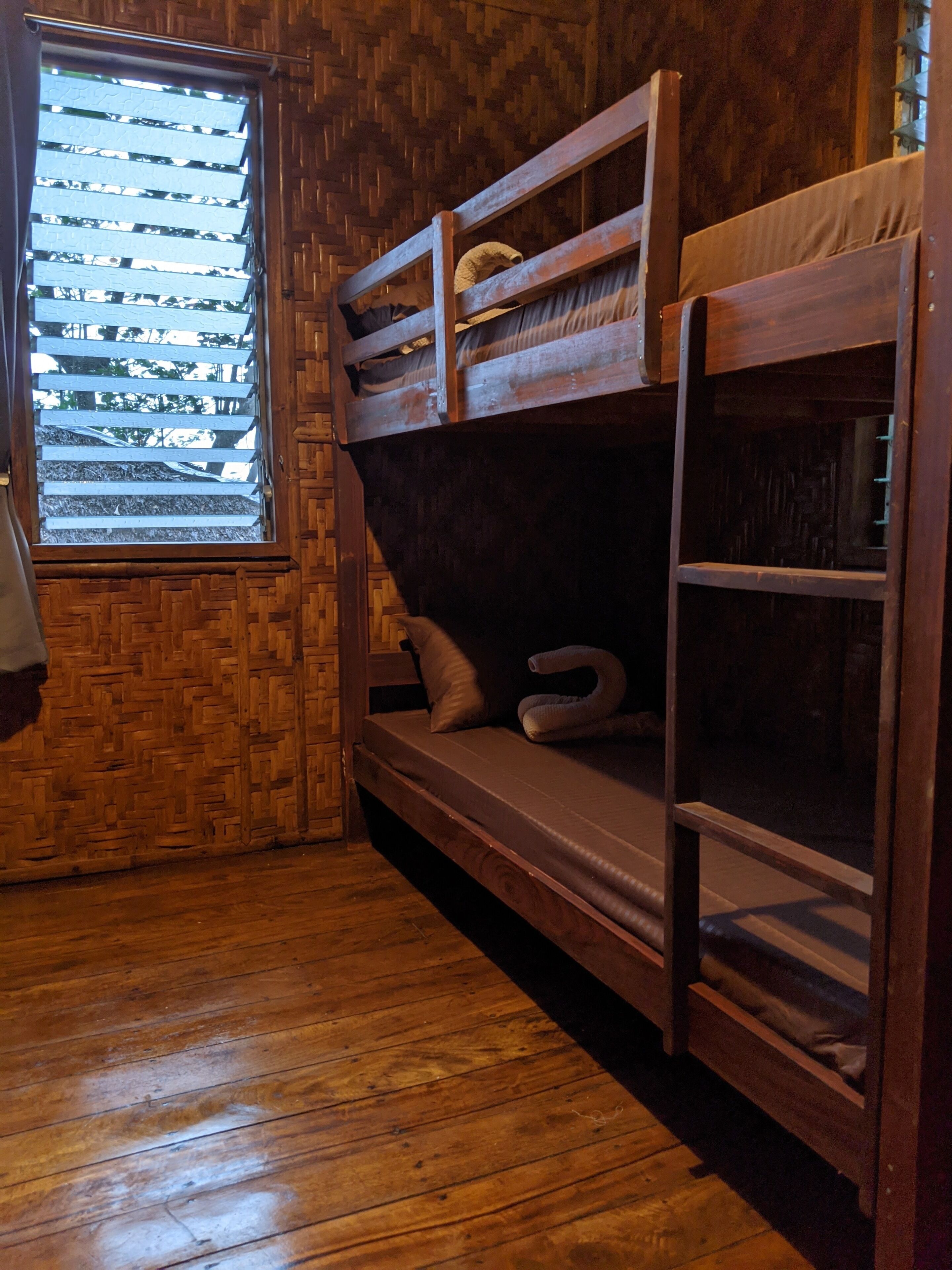 Habitación con dos camas literas de madera, ventana y piso de madera.