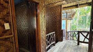 Un interior de madera con una puerta de madera, un pequeño banco de madera y vistas al exterior.