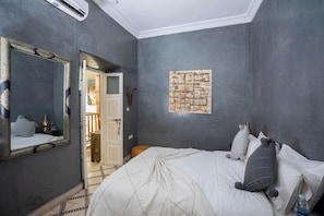 A bedroom with a large bed, a mirror, and a wall-mounted artwork.
