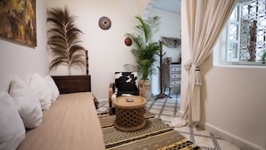 A cozy room with a bed, a round wooden table, a potted plant, and a decorative wall piece. - Riad Miss Caracal (Marrakech)