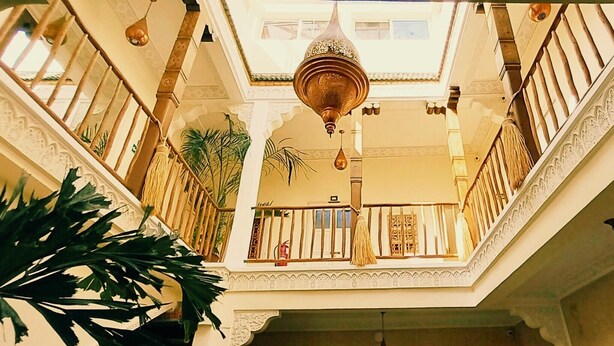 A multi-level atrium with ornate railings, a central hanging light fixture, and potted plants. - Riad Miss Caracal (Marrakech)
