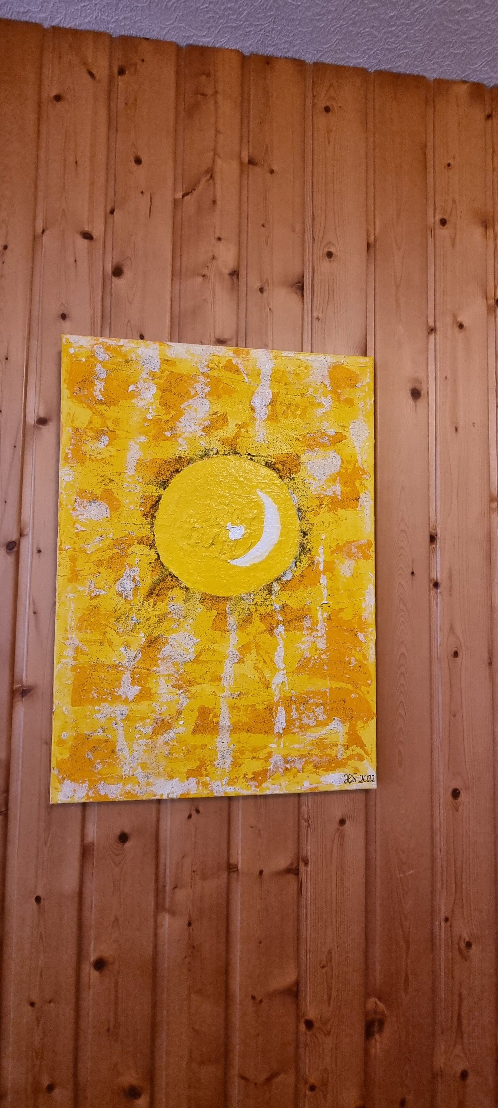 A square painting with a yellow and white abstract design, mounted on a wooden wall.