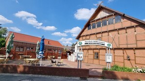 En byggnad av tegel med en skylt där det står ”Varmt välkommen till ölträdgården” och uteservering.
