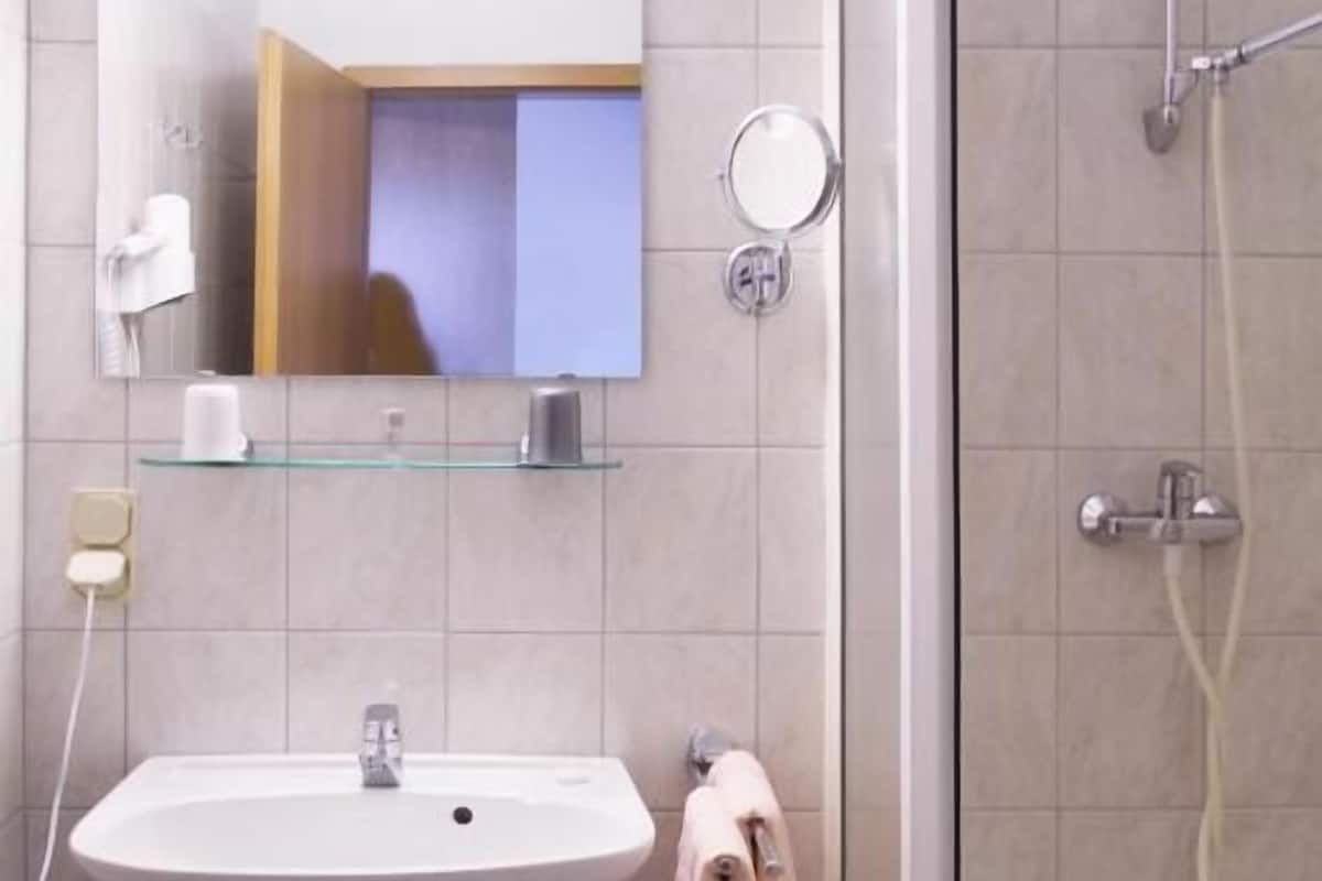 A modern bathroom with a sink, mirror, and shower.