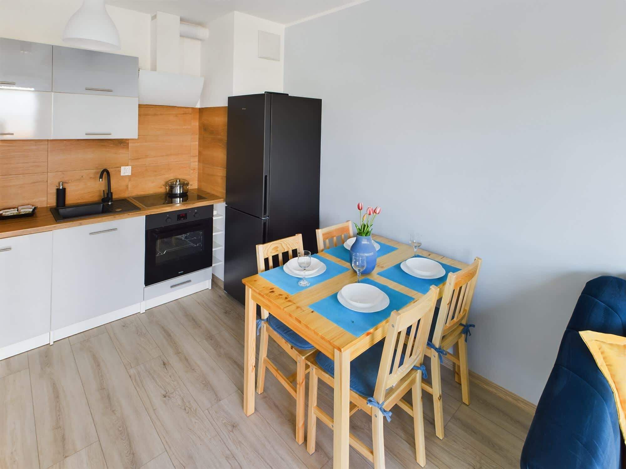 Una cocina compacta con un refrigerador negro, armarios blancos y una encimera de madera.