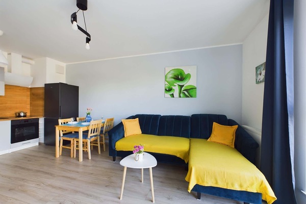 Cosy living room with an elegant, dark blue corner sofa and small coffee table ideal for those, who want to drink a morning coffee in a pleasant atmosphere.